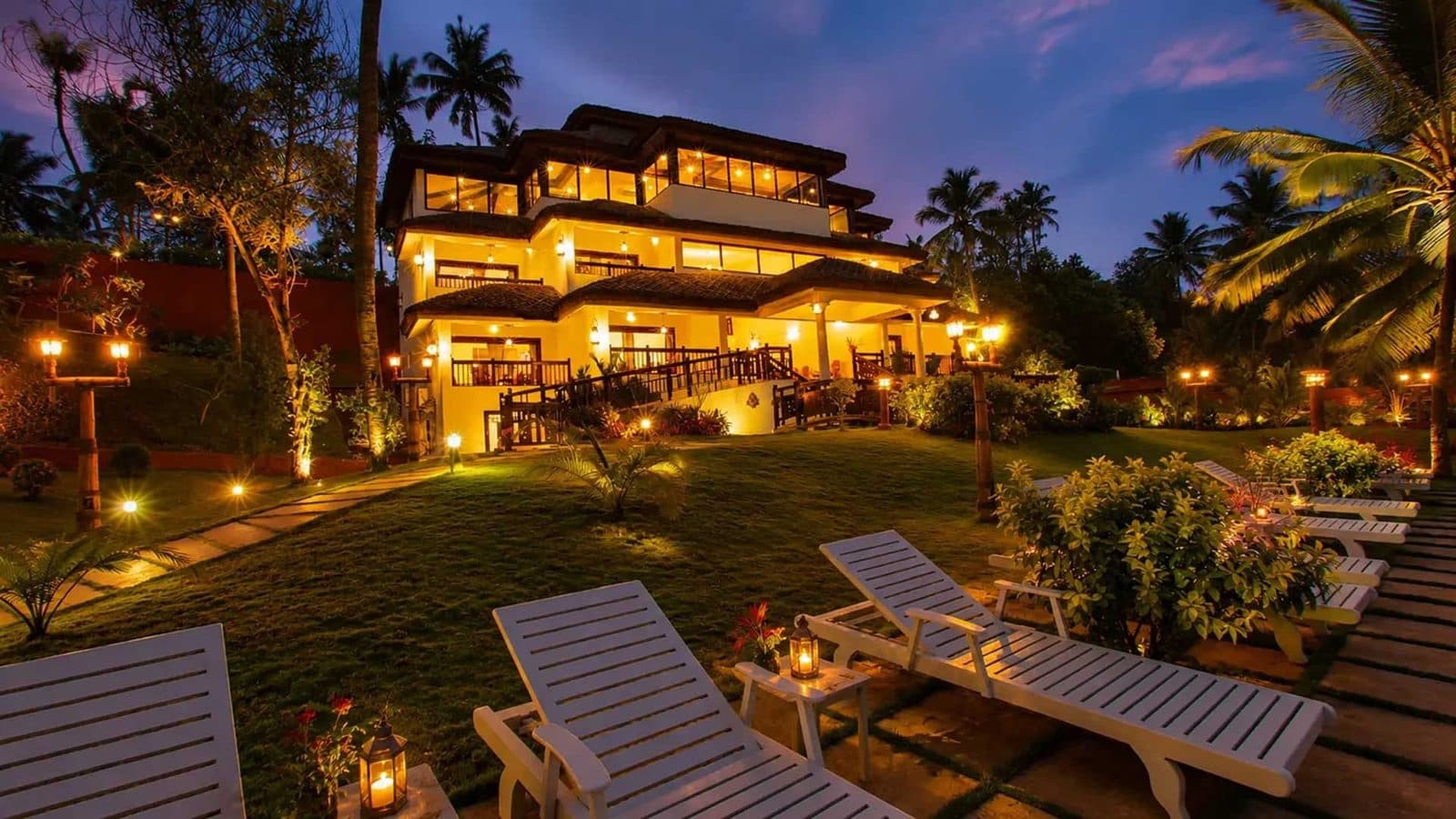 Lake-view rooms with terraces and loungers, lit at dusk